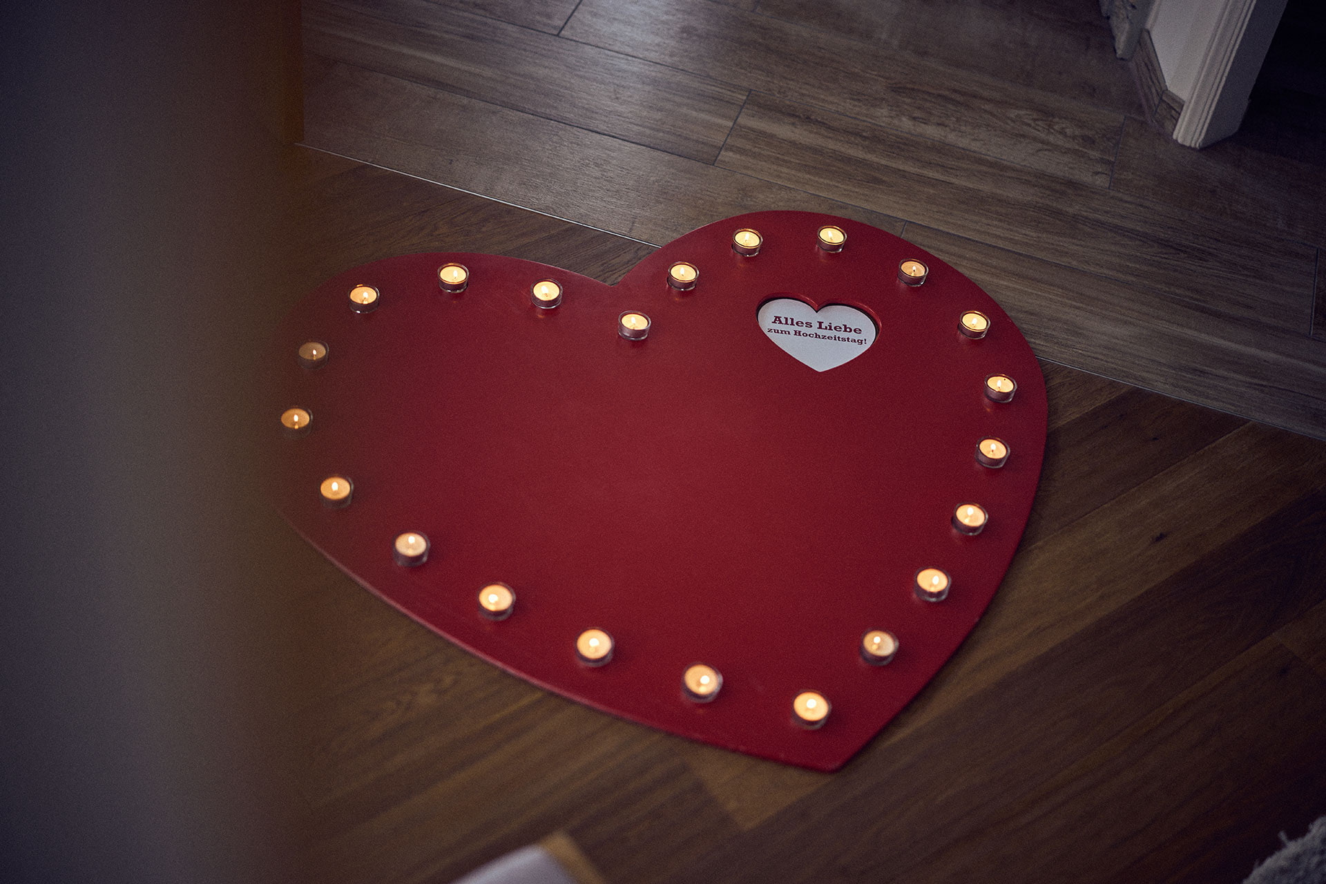 Ein rotes Herz aus Holz mit Teelichtern und einer romantischen Botschaft